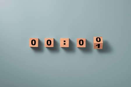 Wooden cube block flipping to change number one to zero on blue background for countdown concept.