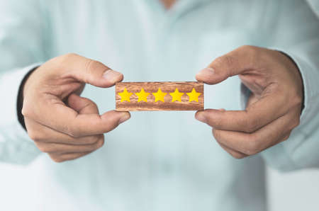 Businessman showing yellow five stars which print screen on wooden block cube foe customer...