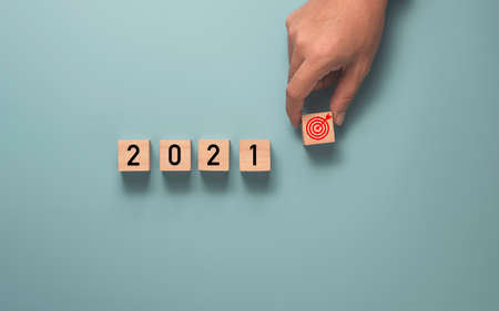 Businessman holding target which print screen on wooden cube block with 2021 year , Setup business target concept.の写真素材