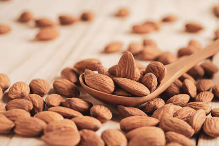 Almonds nut in wooden spoon and pour on table with copy space. Almonds nut is healthy diet food which high protein low fat and essential amino acid.の写真素材