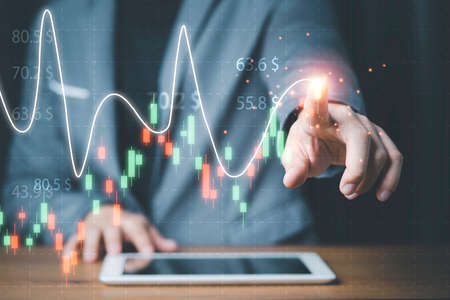 Businessman touching stock market technical chart on virtual screen of tablet for analysis financial...