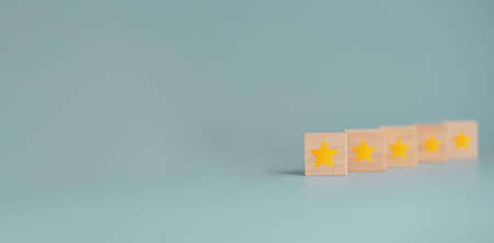 Yellow star print screen on wooden cube block with blue background, customer satisfaction concept of product and service.の写真素材