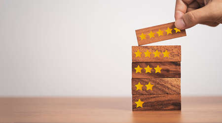 Hand putting five start which print screen on wooden cube block, customer satisfaction for product and service.の写真素材