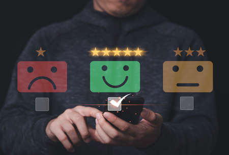 Businessman using mobile and touching to smiley face for customer survey product and service ,...