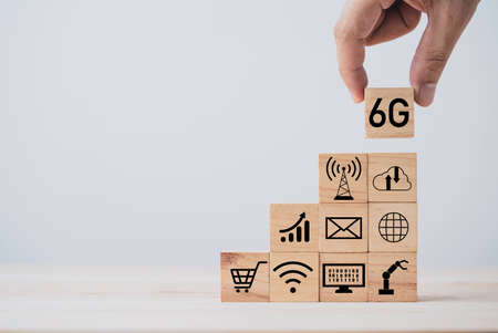 Hand putting 6G which print screen on wooden cube block and technology icon , six generation of high...
