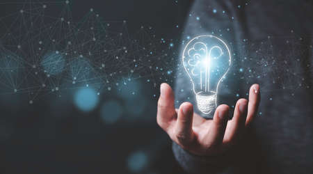 Businessman holding half of virtual lightbulb and brain on blue bokeh background , Smart thinking...
