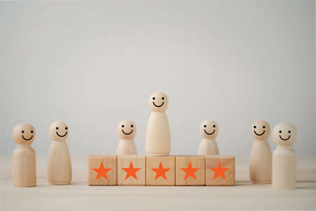 Smiley face on wooden miniature figure with five star on wooden cube for the best customer evaluation and satisfaction product and service.の写真素材
