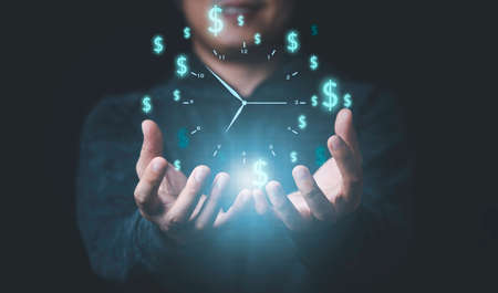 Businessman holding virtual clock with dollar sign for money and time management concept.の写真素材