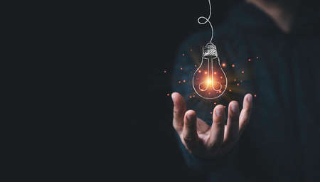 Man hand holding hanging glowing drawing light bulb with orange rays , creative thinking idea and...
