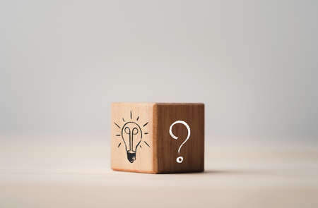 Drawing of light bulb on bright side and question mark on dark side of wooden cube block , problem solving and solution concept.の写真素材