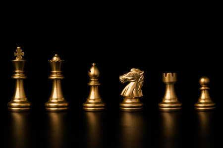 Golden chess include king queen horse ship and pawn on black background.の写真素材