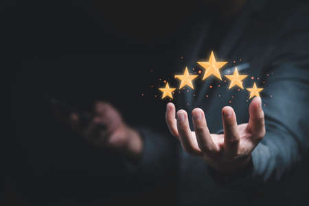 Businessman holding virtual five stars for customer feedback rating and evaluation concept.