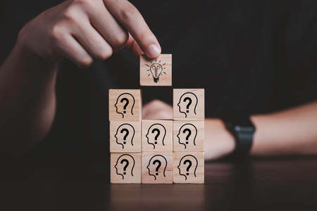 Hand putting wooden cube block stacking which print screen light bulb and question mark with human , Creative thinking idea and problem solving concept.の写真素材