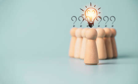 Wooden figure with drawing light bulb on cube in front of other wooden with question mark , Problem...
