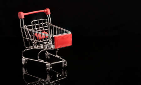 Closeup red shopping trolley cart with reflection on black background , commerce and shopping concept.の写真素材