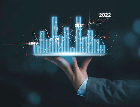 Businessman holding tablet with beautiful bar chart and line graph, economic and business stock investment concept.の写真素材