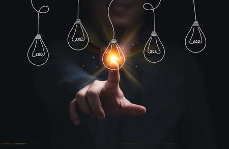 Businessman hand touching glowing lightbulb among lamp does not light for selective creative smart thinking ideas and innovation concept.の写真素材