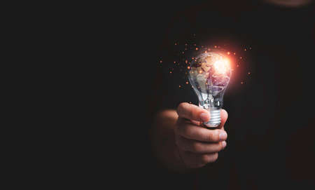 Businessman holding planet inside of lightbulb for earth day and saving energy environment concept