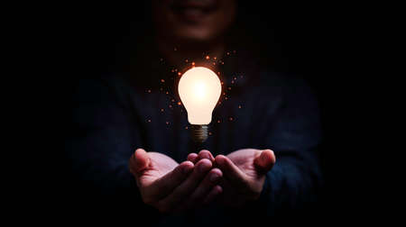 Businessman holding glowing lightbulb for creative thinking and problem solving concept.の写真素材