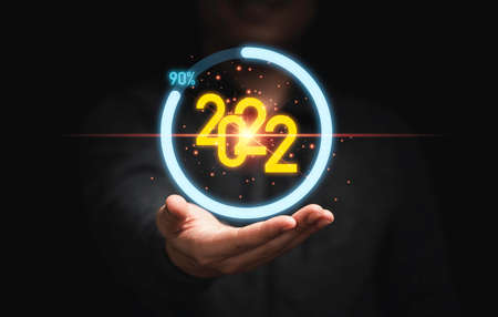 Businessman holding virtual 2022 number and download percentage progress on dark background for merry Christmas and happy new year concept.の写真素材