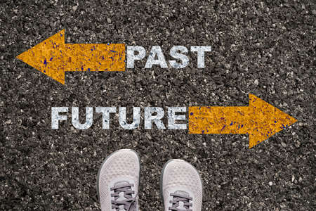 Shoes on asphalt road with yellow opposite arrow and past future wording concept.の写真素材