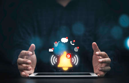 Businessman protecting tablet with virtual yellow bell ringing and icons for application...