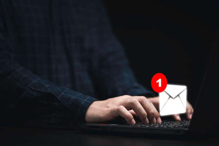 Businessman using laptop computer with white newsletters and notification for business e-mail and...