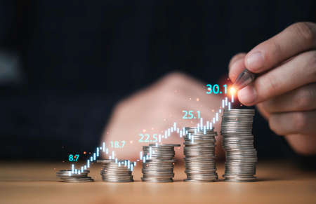 Hand writing stock market graph and chart with increasing coins stacking for business investment...