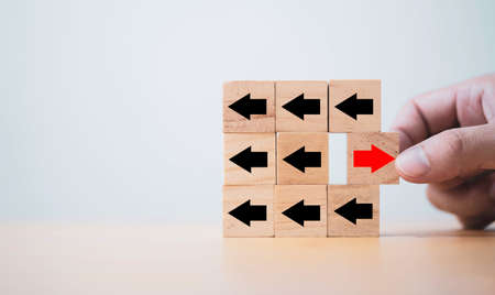 Hand pull out red arrow red arrow which print screen on wooden cube block and opposite direction...