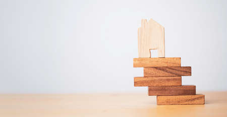 Wooden house model lay on edge of wooden stacking for risk asset management and insurance of real estate concept.の写真素材