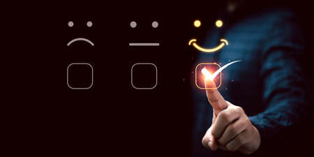 Businessman touching virtual touch screen to select smiley face emotion button for the best...