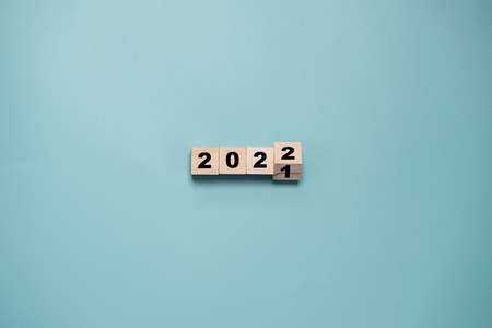 Wooden cube block flipping from 2021 to 2022 on blue background , preparation for merry Christmas and happy new year and 3d rendering concept.の写真素材