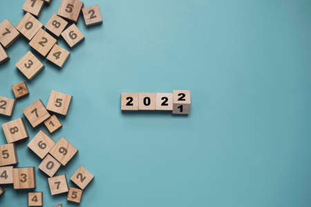 Flipping of wooden cube block for change 2021 to 2022 with other number on blocks on blue background for merry Christmas and happy new year , Start New business and plan concept.の写真素材