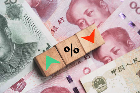 Increasing and decreasing sign with percentage on wooden cube block and Yuan banknotes for forex currency exchange money transfer rate concept.の写真素材