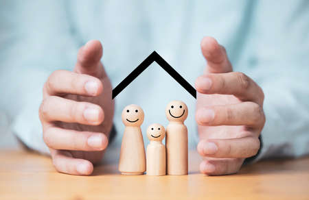 Businessman two hands protecting family wooden model for insurance and assurance life concept.の写真素材