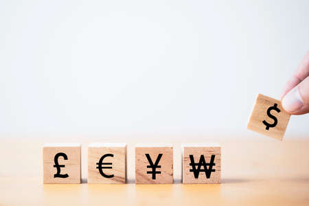 Hand putting dollar sign which print screen on wooden cube block for currency exchange and money transfer concept.の写真素材