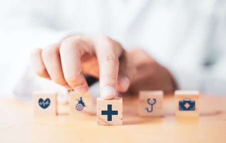 Doctor pushing wooden block cube which print screen health care and medical icons for healthy and...