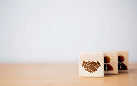 Hand shaking which print screen on wooden cube block  in front of human icon for business deal and agreement concept.の写真素材