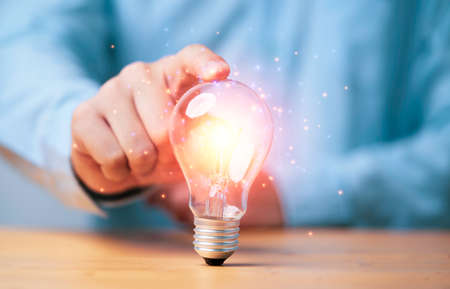 Hand touching to glowing lamp or lightbulb for creative thinking idea and problem solving or solution concept.の写真素材