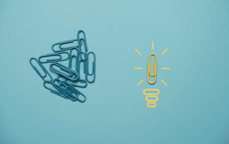 One of yellow paper clip move out from group blue clip which metaphor as lamp with glowing for...