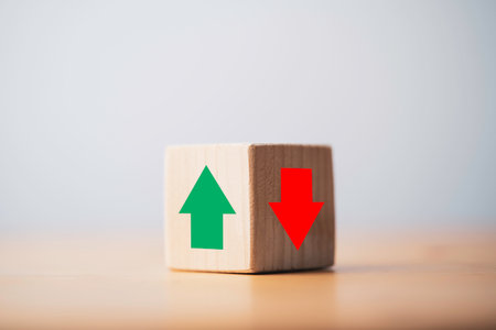 Focus of green up arrow in bright side and red down arrow in dark side which print screen on wooden cube block for economic and business profit growth concept.の写真素材