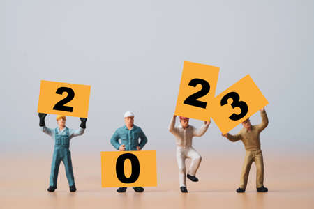 Miniature worker showing 2023 on yellow board for preparation merry Christmas and happy new year concept.の写真素材