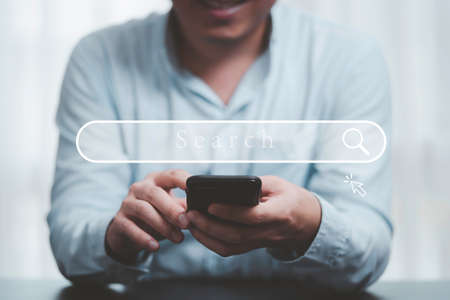 Hand using mobile phone  with search icon for Search Engine Optimisation or SEO concept to find information by internet connection.の写真素材