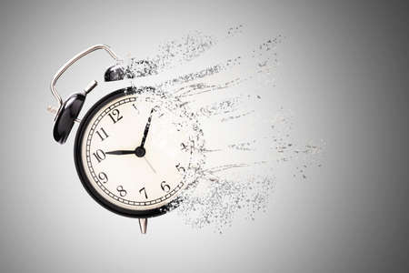 Retro black alarm clock dissolving into a little particles for time can not return and never wait anyone , Time management concept.の写真素材