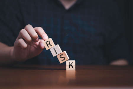 Hand touching to collapse block and printing risk wording for risk management concept.の写真素材