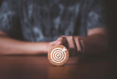 Hand  touching and push target board which printing on wooden round block  for creative and set up business objective target  goal concept.の写真素材