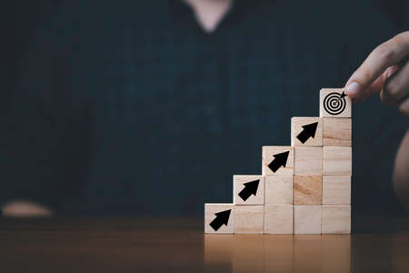 Hand putting and stacking virtual target board and arrow which print screen on wooden cube. Business achievement goal and objective target concept.の写真素材
