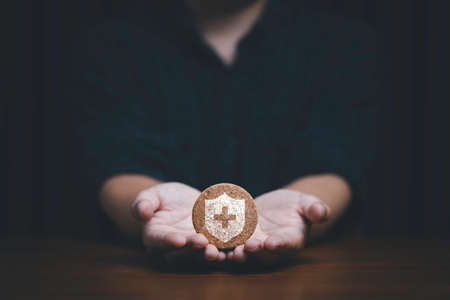 Hand showing insurance sign which print screen on round wooden for healthcare assurance claim and medical concept.の写真素材