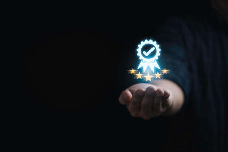 Businessman holding and showing the best quality assurance with golden five stars for guarantee product and ISO service concept.の写真素材