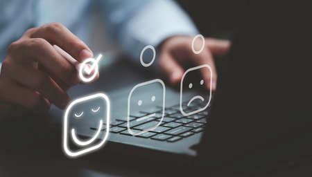 Businessman tick mark to select smiley face icon for client evaluation and customer satisfaction after use product and service concept.の写真素材